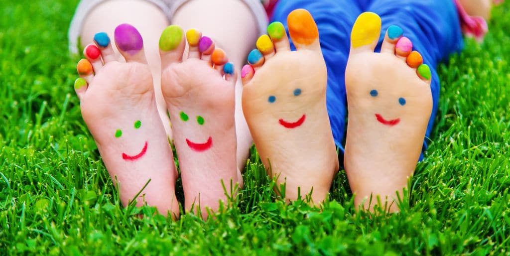 Pies de niños pintados sonrientes sobre el césped