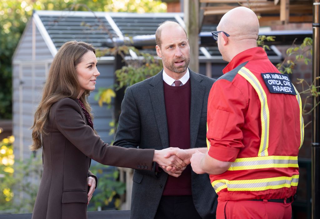 Plano medio de Kate Middleton y Guillermo de Inglaterra saludando a un miembro de los servicios de emergencia en Southport