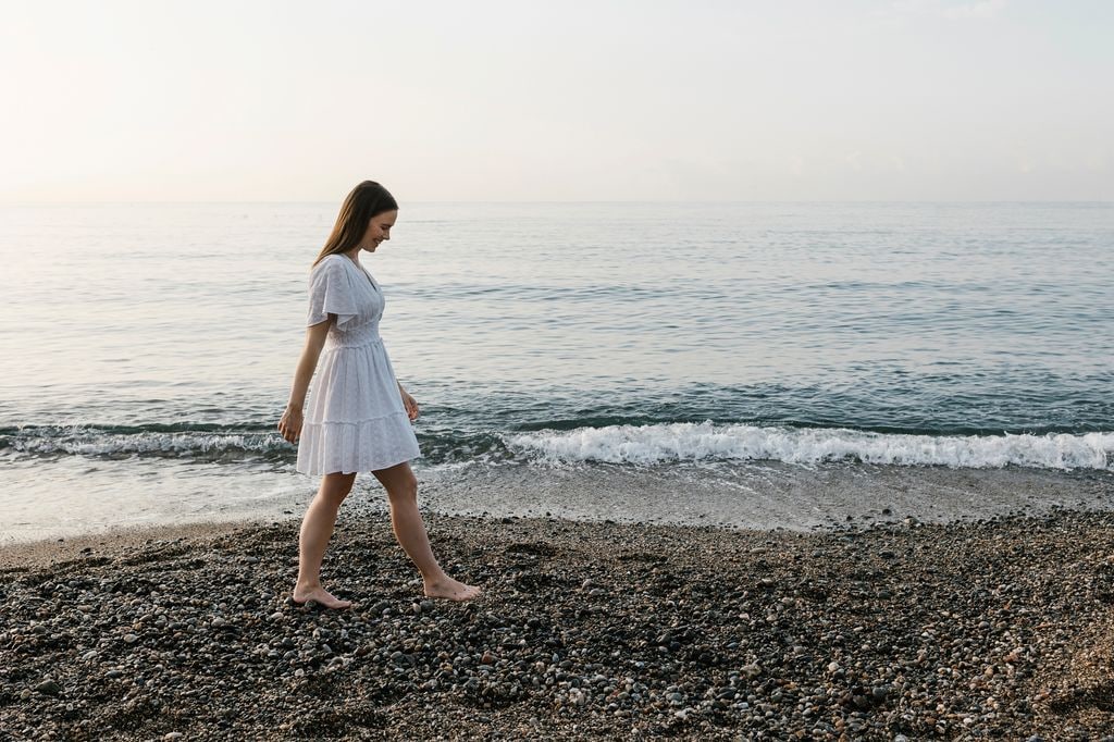 mujer relajada caminando por la playa sobre la arena