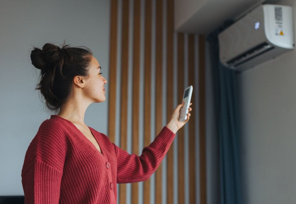 Una mujer encendiendo el aire acondicionado de su casa