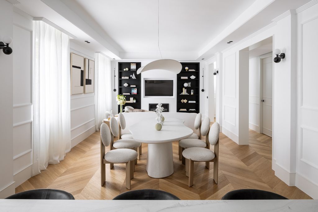 Salón comedor blanco con molduras y estantería negra. 
