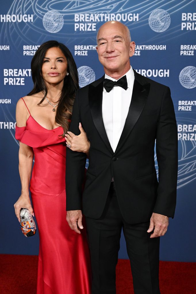 Lauren Sánchez con vestido rojo vintage y Jeff Bezos con esmoquin negro posan en la alfombra roja del Premio Breakthrough 2025.