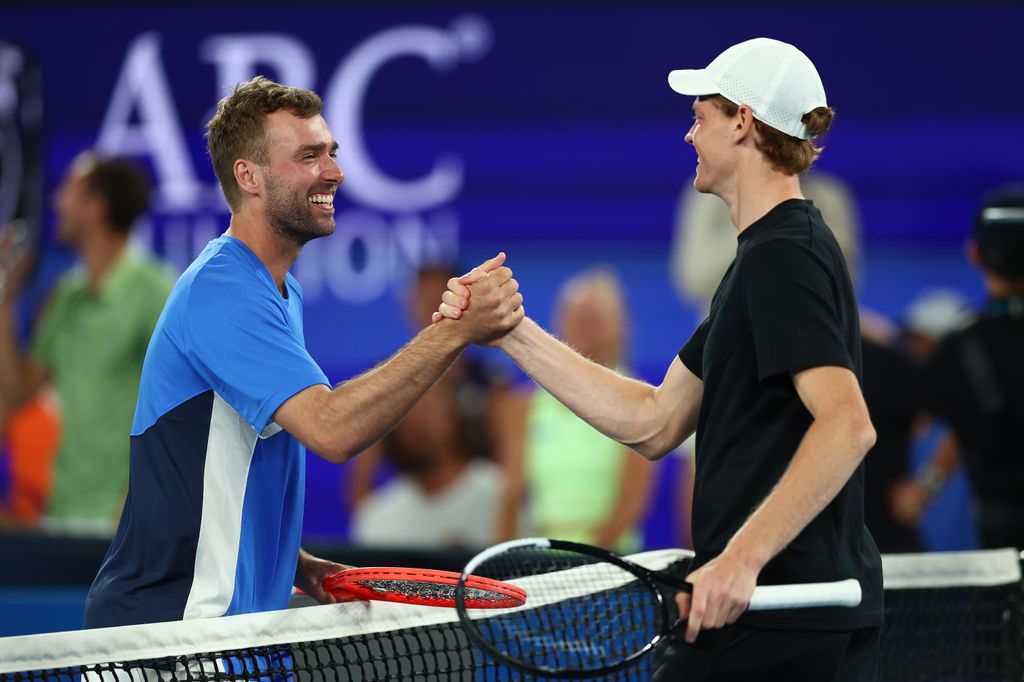 Jordan Smith sonríe mientras saluda a Jannik Sinner en la pista del Rod Laver Arena, tras protagonizar uno de los momentos más insólitos del One Point Slam previo al Abierto de Australia