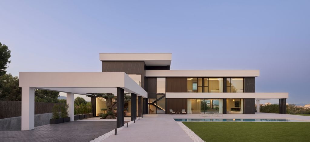 Vista al atardecer de una vivienda unifamiliar con todas las luces encendidas