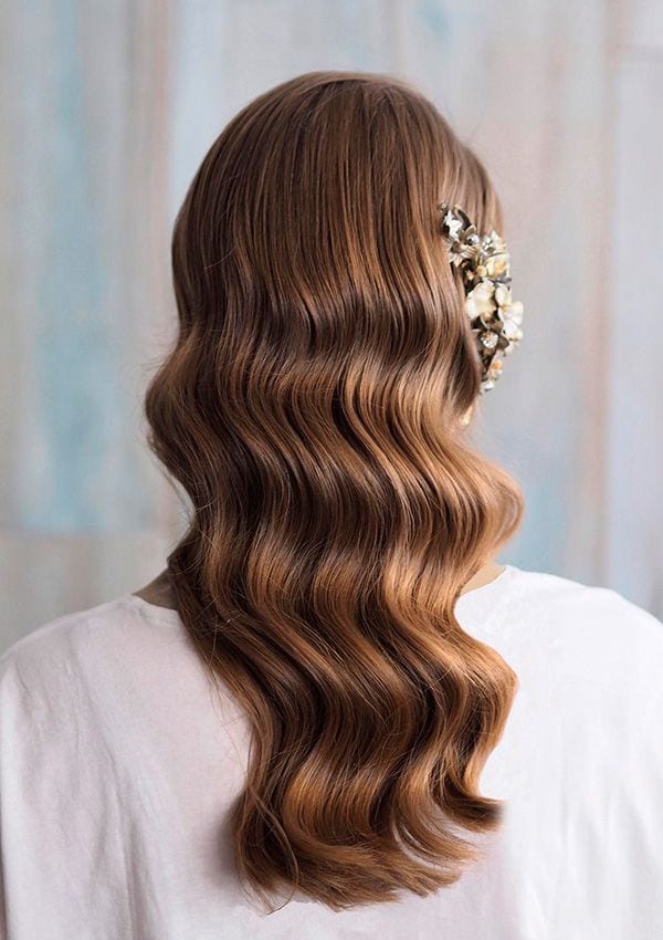 Peinado de novia con ondas al agua y horquilla de flores, de MG Beauty