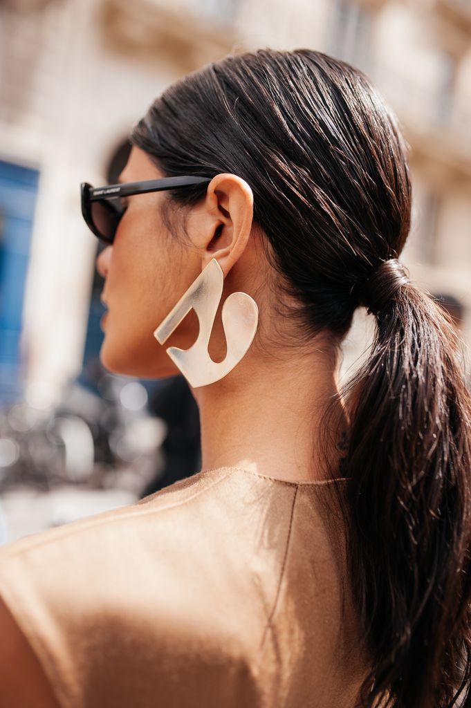 Invitada a la Semana de la Moda de París con coleta larga y pendientes plateados