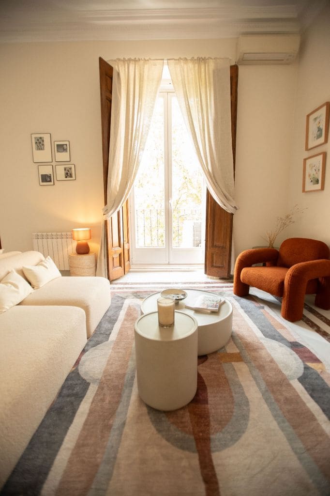 Rincón del salón con sofá blanco y butaca terracota