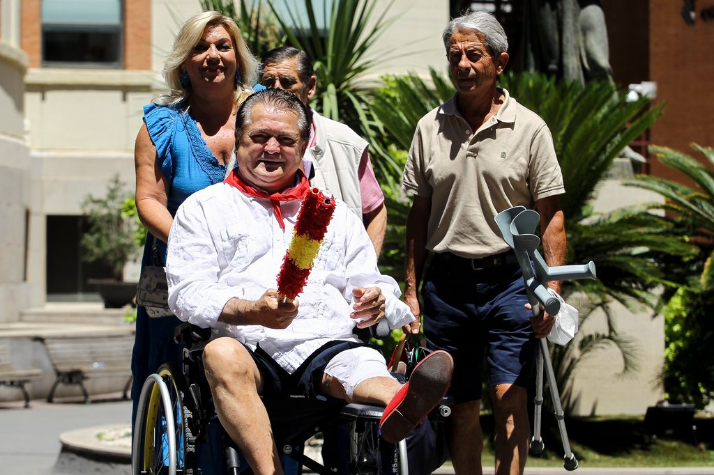 Plano medio de Vicente Ruiz 'El Soro' saliendo del hospital en silla de ruedas con su mujer