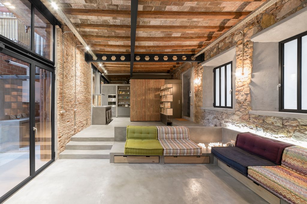 Salón con suelo de microcemento y paredes de piedra vista