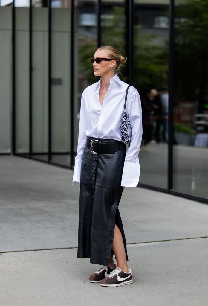 Look con falda de cuero midi, camisa blanca y zapatillas