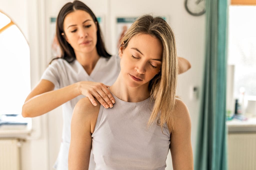 mujer joven con dolor de cuello en la consulta de la fisioterapeuta