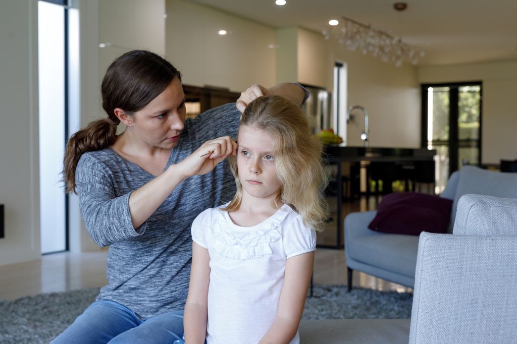 Madre revisando la cabeza de su hija por si tiene piojos