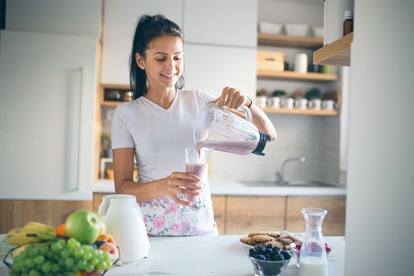 Mujer preparándose un batido para desayunar