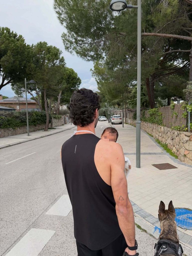 Juanito Iglesias pasea al perro de la familia con uno de los bebés en los brazos