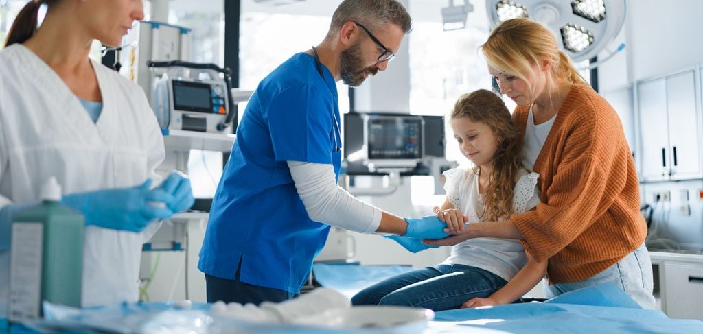 niña pequeña en la consulta del médico, haciéndose una cura en la mano