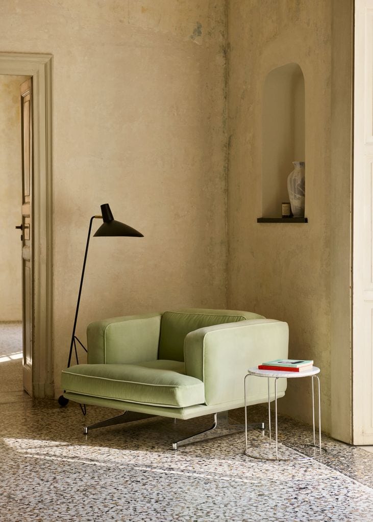 Rincón de lectura con sillón verde y lámpara de pie negra