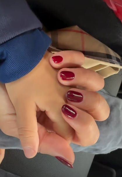 Hiba Abouk de la mano de su hijo con manicura granate