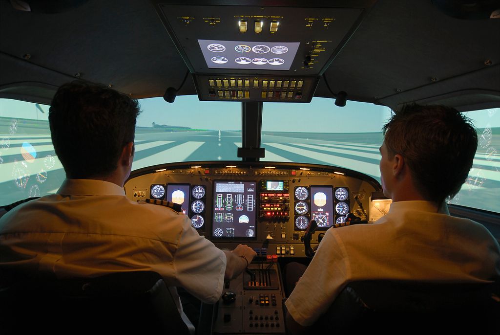 Dos pilotos dentro de la cabina de vuelo. Aparecen de espaldas y manejando 