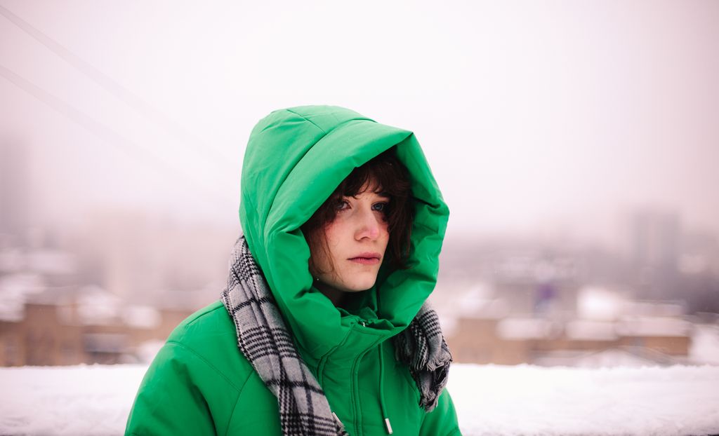 Mujer con plumífero verde en un fondo nevado