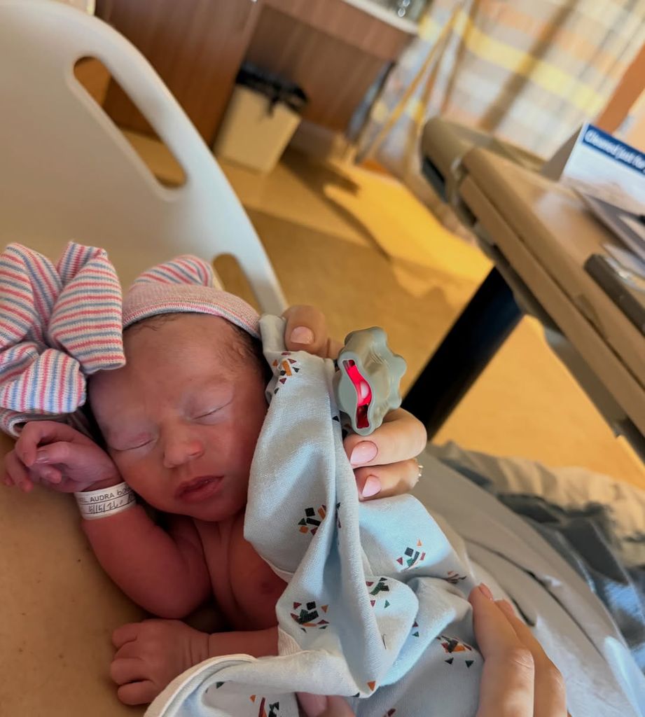 La modelo descansa en la cama del hospital con la pequeña acurrucada 