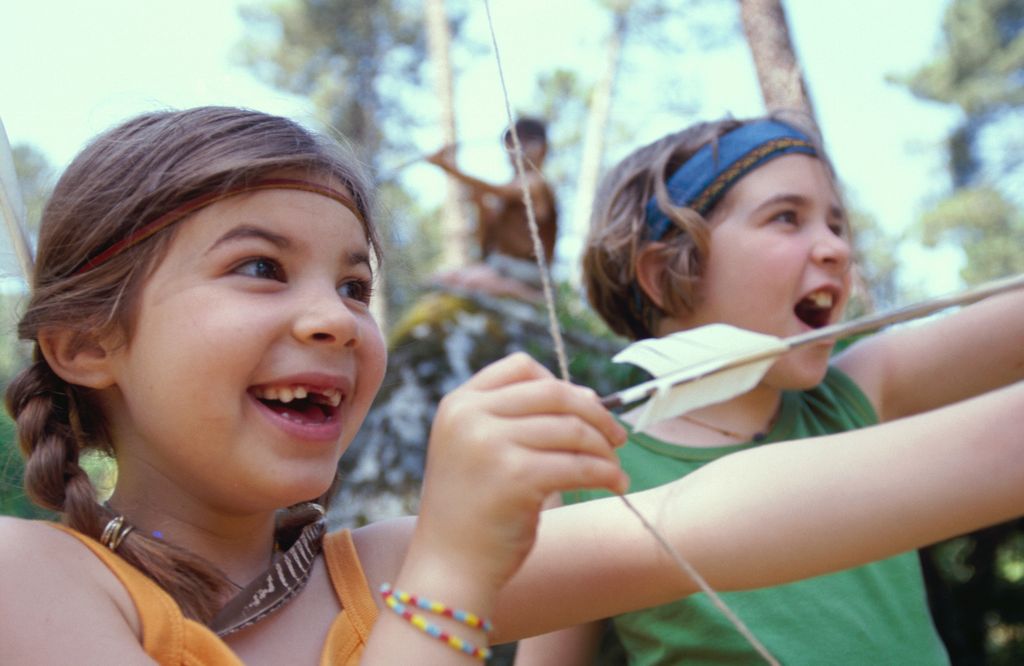 Niñas en campamento de verano tirando con arco