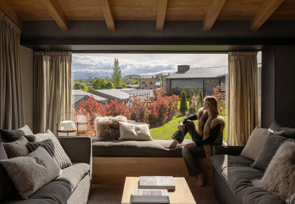 Salón con dos sofás enfrentados y, junto al ventanal, un banco corrido que configura un minirefugio