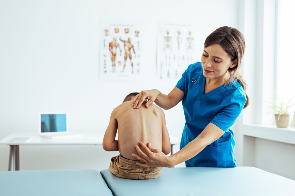 Médico examinando la escoliosis de un niño