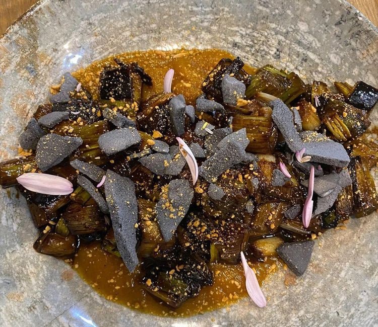'Calçots' salteados con soja y ajo negro al wok, puré de calabaza y ceniza