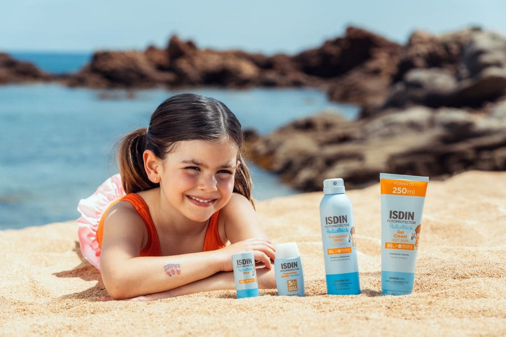 Niña en la playa con productos de protección solar