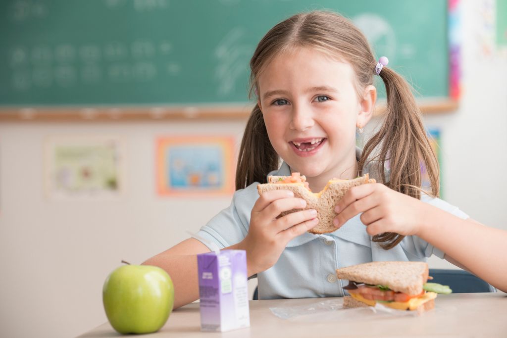 Niña tomando la merienda en el colegio