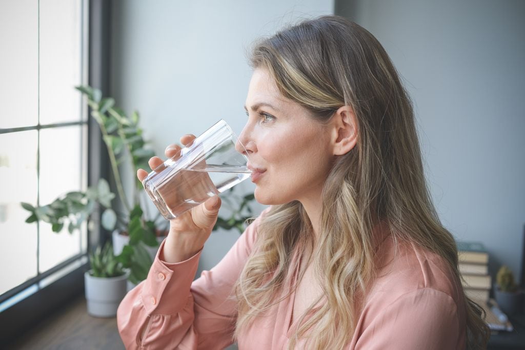 mujer de mediana edad bebiendo un vaso de agua
