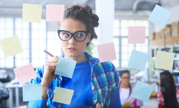 Mujer delante de un muro de cristal lleno de post-it