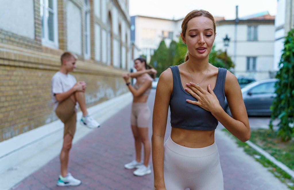 Mujer haciendo deporte con problemas para respirar, con su mano en el pecho