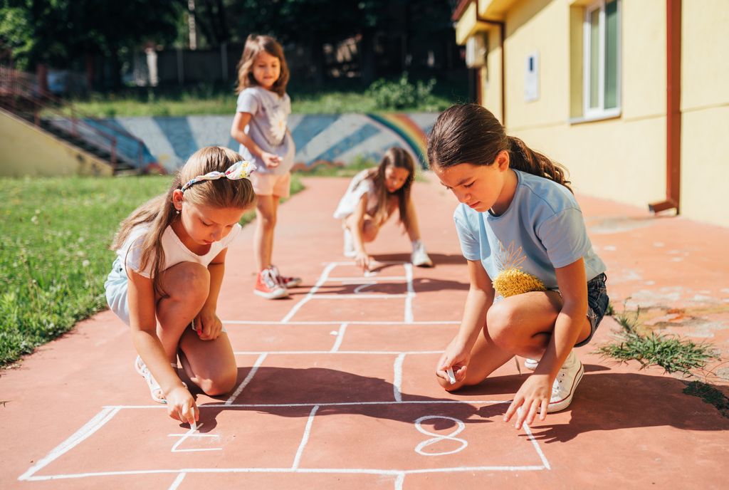 niñas pintando en la calle una rayuela para jugar