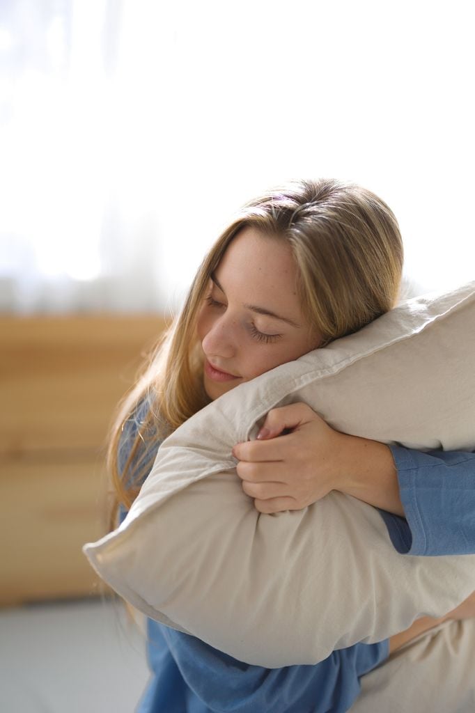 Mujer abrazando un almohadón síntoma de buena autoestima