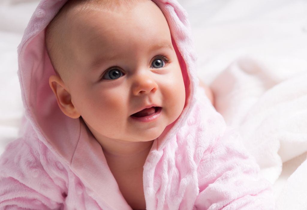 Bebé niña con rostro dulce y ojos claros lleva albornoz rosa
