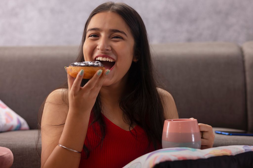 adolescente comiendo un donut con un café