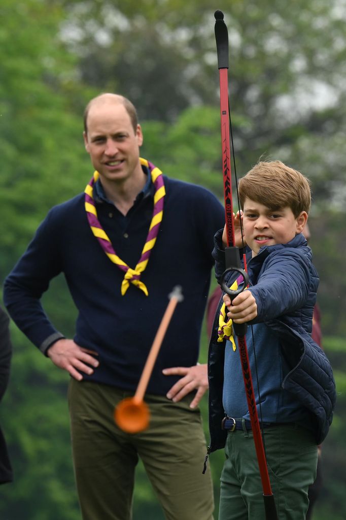 Plano medio del príncipe Guillermo con su hijo George en una actividad de tiro con arco