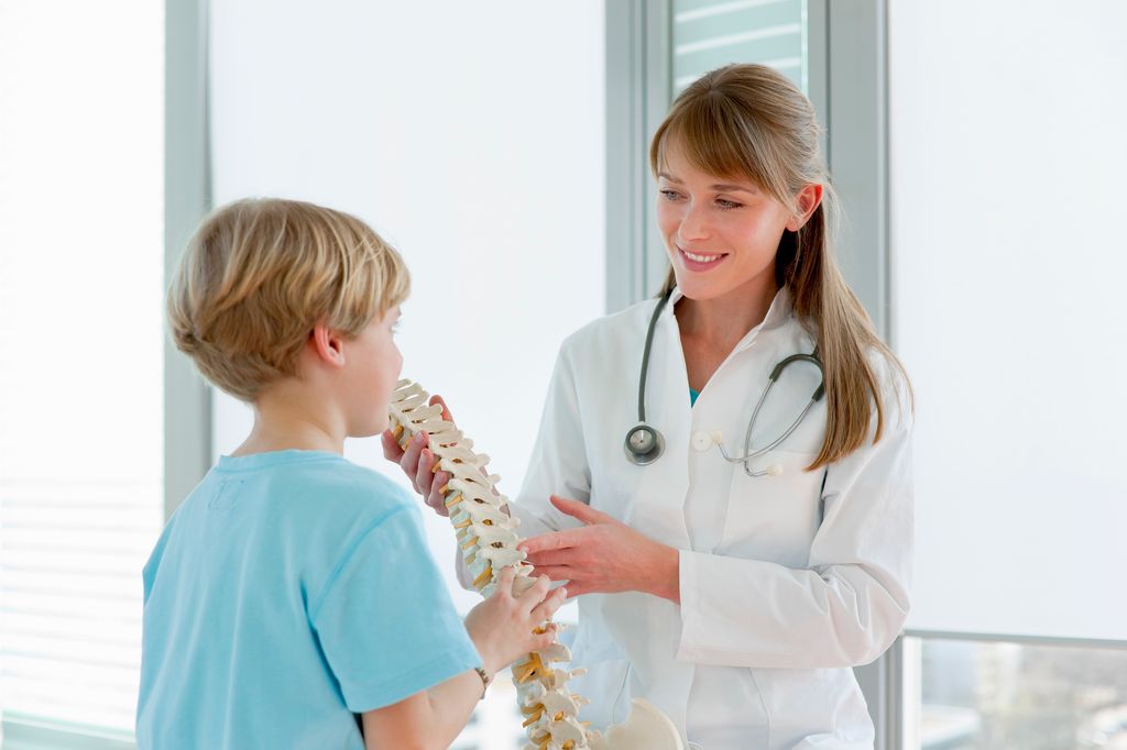 Médico explicando a un niño cómo es la columna vertebral