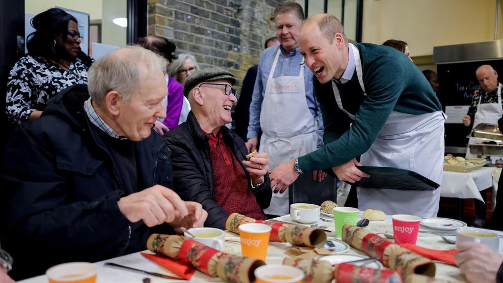 Plano medio de Guillermo de Inglaterra saludando a personas en un restaurante