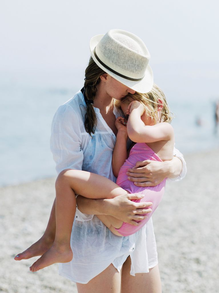 madre cogiendo en brazos a su hija en la playa