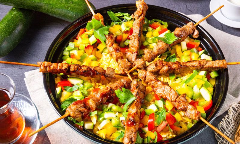 Brochetas de cordero con arroz al curry y vegetales
