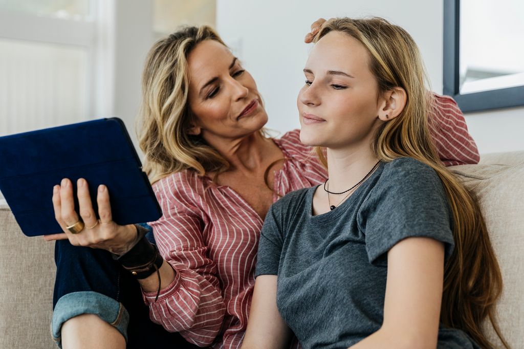 madre junto a su hija adolescente sentadas en el sofá