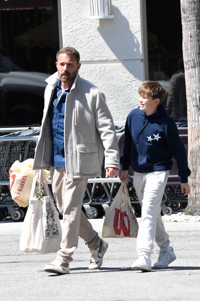 04/20/2025 Ben Affleck is pictured out shopping with his son Samuel on Easter Sunday in Los Angeles. The 52 year old American actor hit up Wold Market sporting a blue top and tan trousers. Ben could be seen discretely loading a  DC Batman Hush Version Figure into his car.