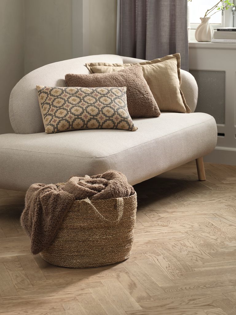 Cesta de fibra con mantas junto al sofá