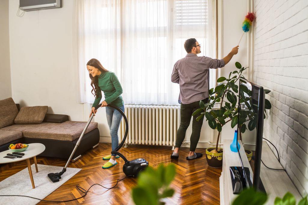 Pareja limpiando el salón. 