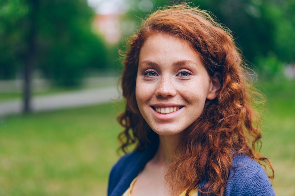 Chica adolescente pelirroja sonriente al aire libre