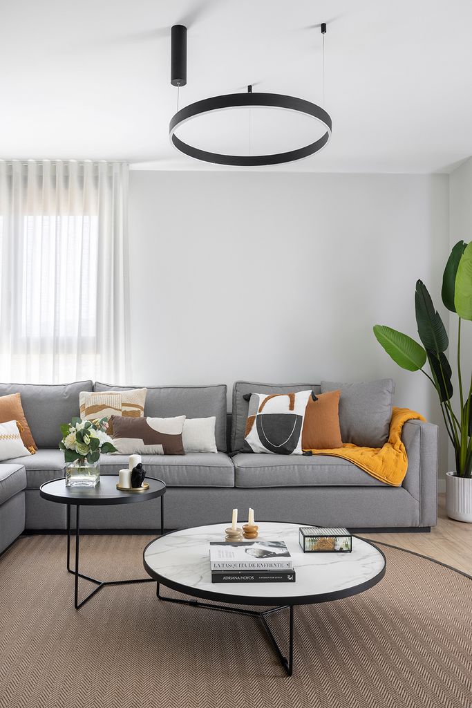 Salón con sofá gris y cojines con estampado.