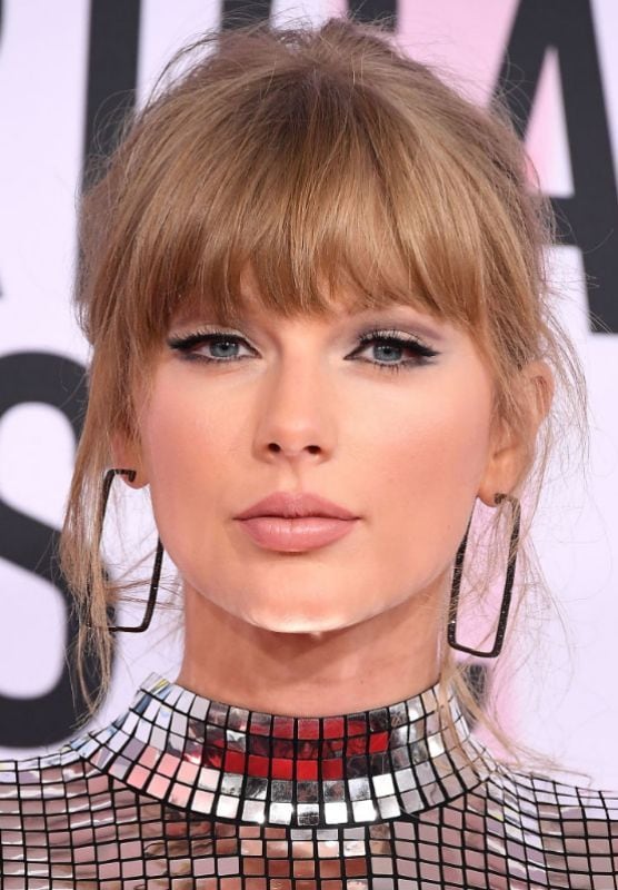 Taylor Swift con flequillo recto y moño desenfadado con vestido metalizado 