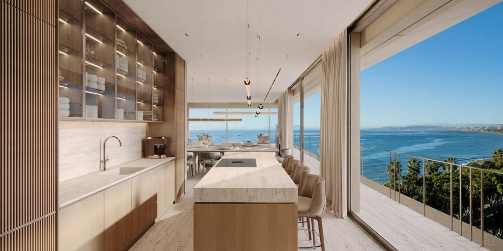 Cocina moderna con isla, un espacio volcado al paisaje marino. Al fondo, abierto, el comedor